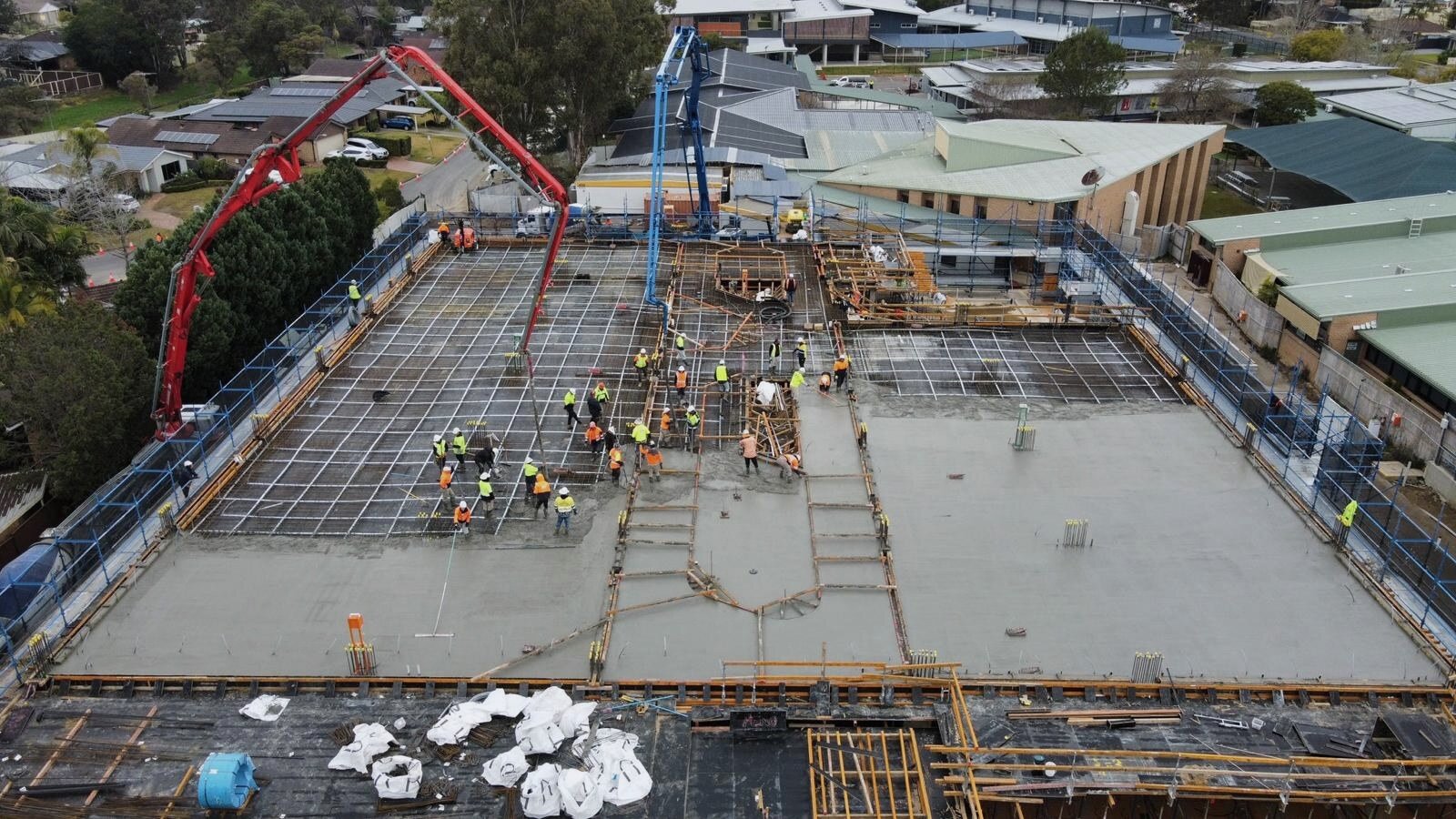 Boom pumping suspended decks over a school campus, aerial view