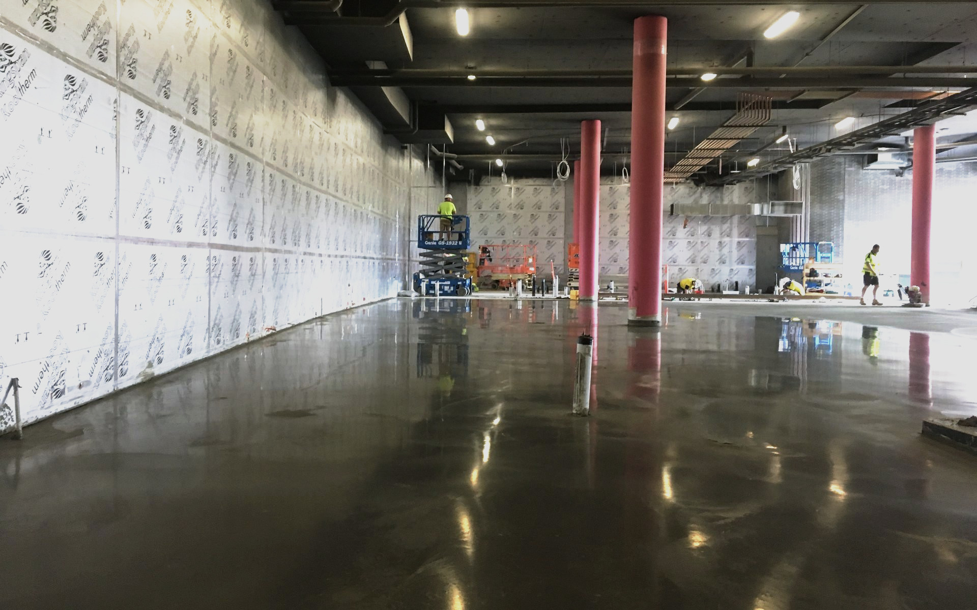 Freshly burnished coolroom slab inside insulated panel walls, finishing work continuing beyond